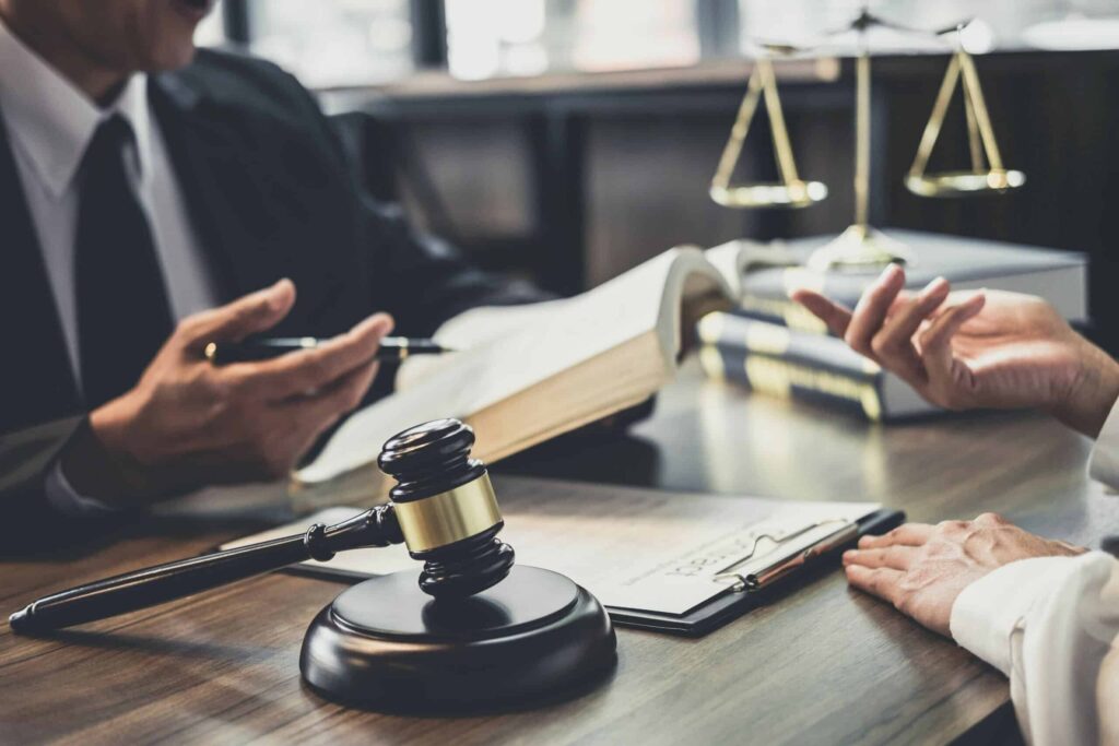 Lawyer discussing legal documents with a client at a desk with gavel and scales.