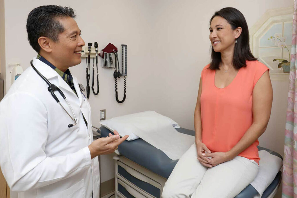 Doctor talking with a patient sitting on an exam table.
